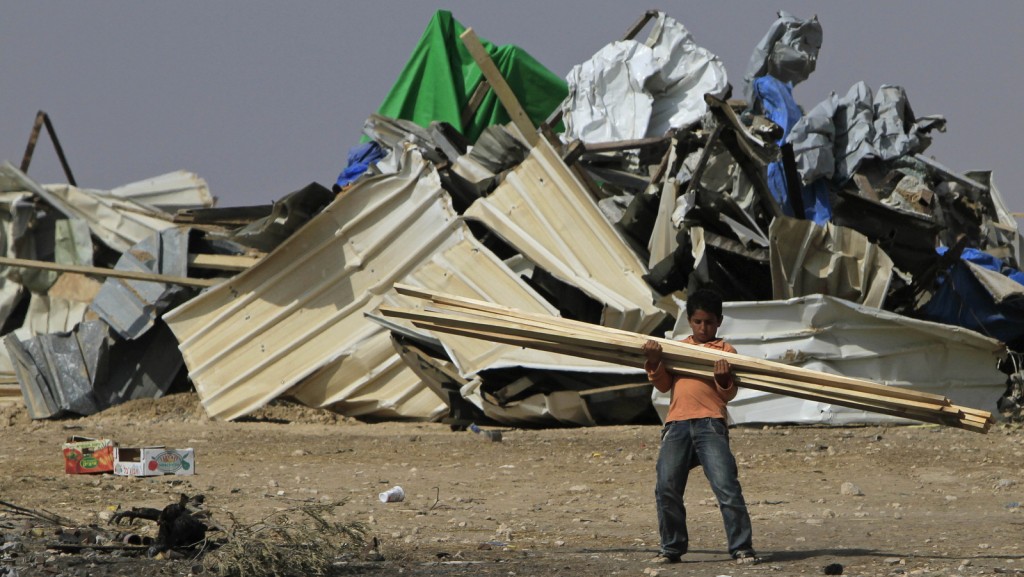 A Bedouin boy carries timber after police removed temporary shacks from the site earlier, in the village of El Araqib near the southern Israeli city of Beersheba, Wednesday, Aug. 4, 2010. Israeli police removed several shacks from El Araqib Wednesday following last week's demolition of some 35 houses, on land the local residents identify as their property but which Israel's government says is owned by the state. (AP Photo/Tsafrir Abayov)