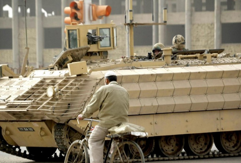 A man rides his bicycle past a British armoured vehicle near the site of a roadside bombing in Basra in February 2007. click to enlarge
