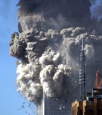 Above: the top section comprising 30 floors of the South Tower has broken off. As Hufschmid describes: 'The white clouds show that the pulverizing process is occurring in the portion of the tower that is below the fire zone.' [Painful Questions, p. 47]